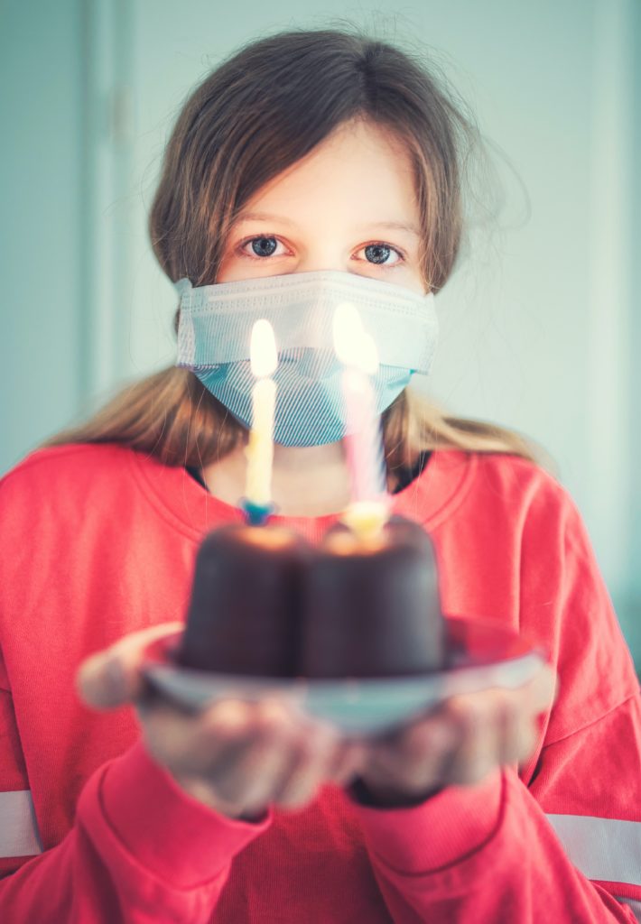 girl holding birthday cake and wearing a face mask; photo by pixpoetry on Unsplash